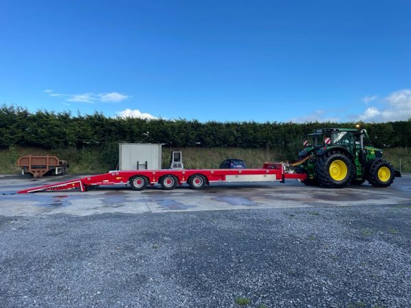 red low loader attached to tractor